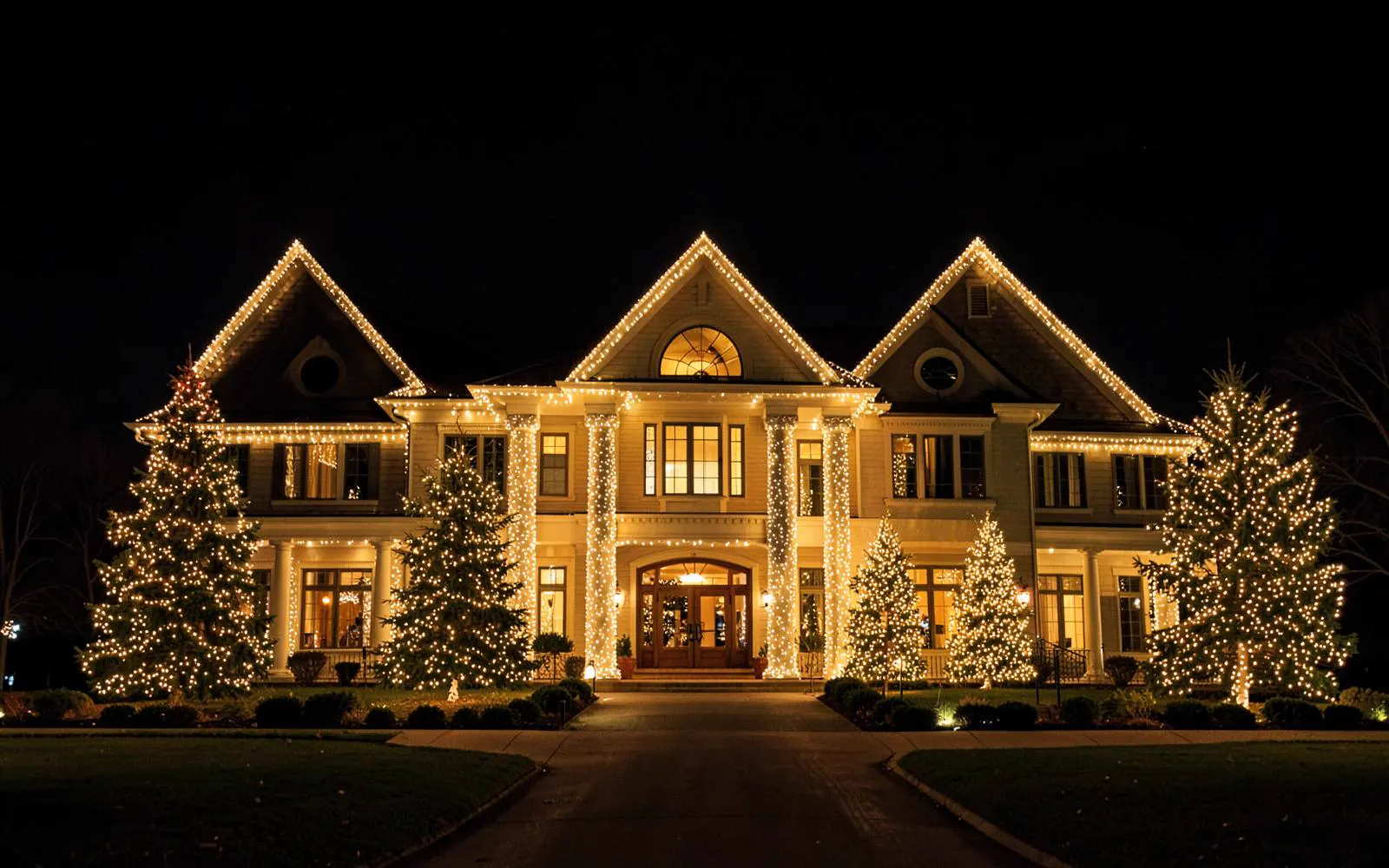 Large professional holiday lighting display with warm white roofline lights